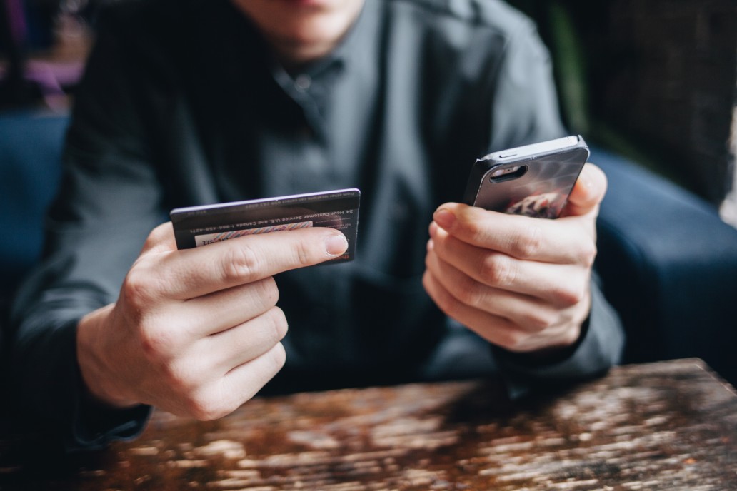 Photo d'un homme regardant sa carte bancaire et son smartphone